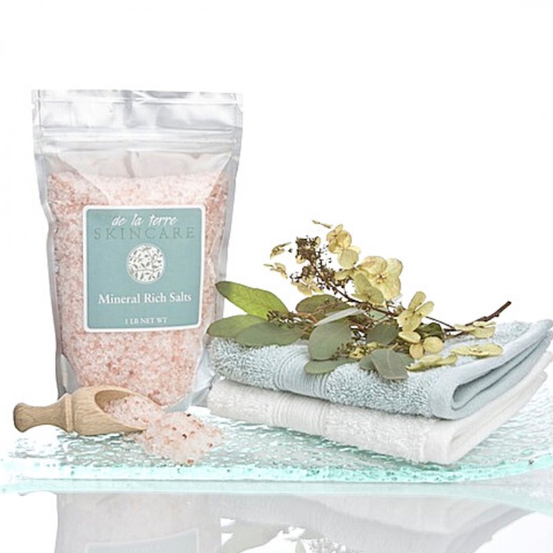 “Mineral Rich Salts by De La Terre Skincare in resealable pouch with folded towels and wooden scoop”